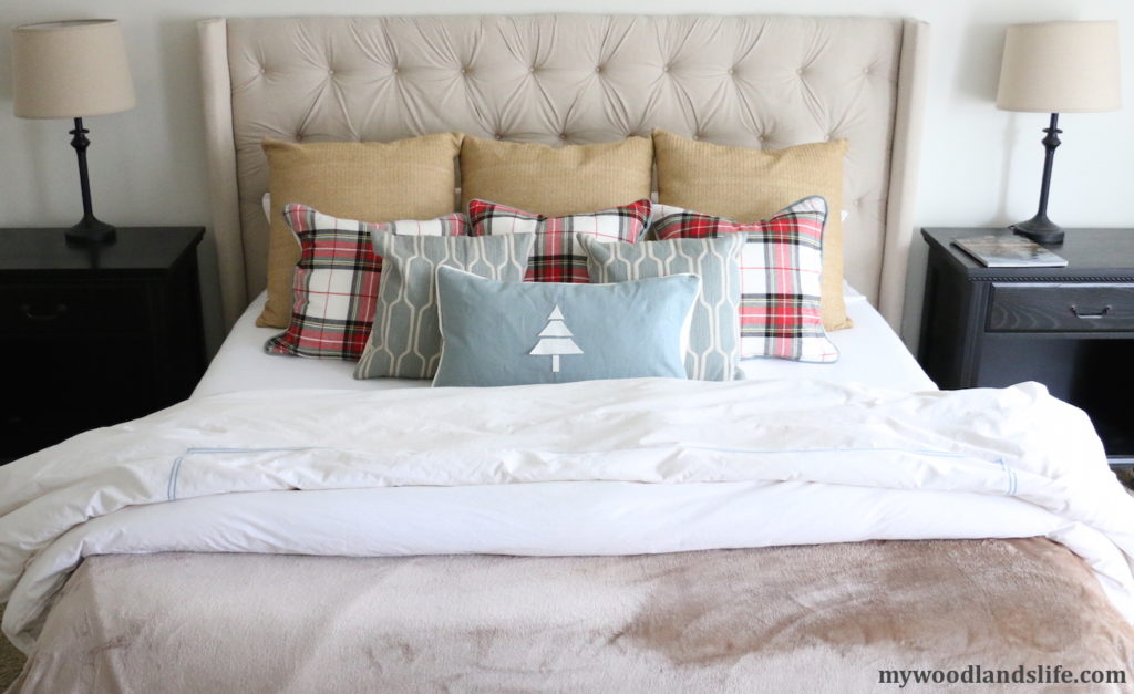 Adding plaid pillows to white bedding for muted Christmas bedroom decor