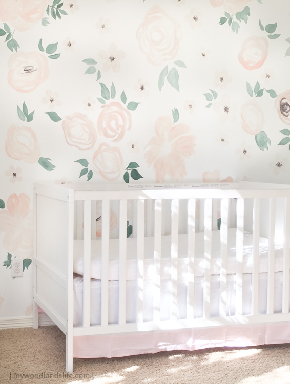 Girls nursery with floral pattern wall and white IKEA crib