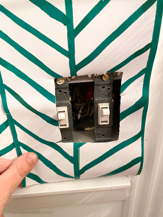 Chevron green peel and stick wallpaper around light switch receptacle