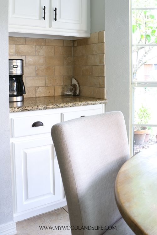 Coffee maker, sweetener, and coffee filters in napkin holder on kitchen countertop behind kitchen table