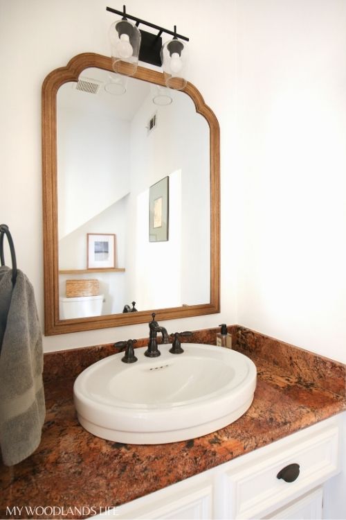 Powder room sink and countertop with updated wood mirror and modern light fixture