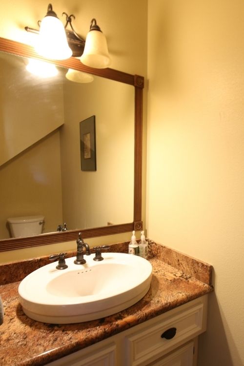 Powder room sink and countertop with framed mirror and light fixture