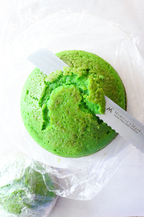 Green cake being cut by serrated knife
