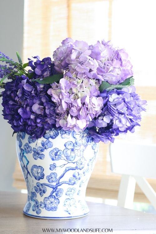 Blue and white floral vase with light and dark purple hydrangeas