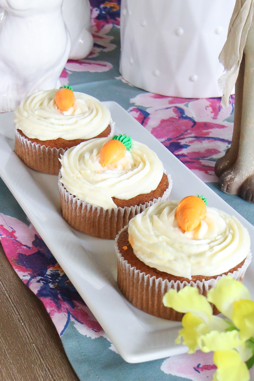 Mini carrot cakes on white serving tray with blue and pink floral table runner underneath